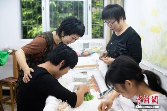 图为5月7日，潮州市鸿辉礼服厂的设计总监佘丹晖(左一)在她母亲康惠芳的工作室和绣娘讨论潮绣。 中新社记者 陈楚红 摄