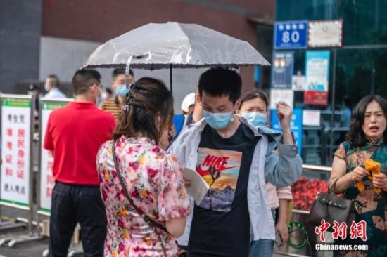 6月7日，成都玉林中学考点外，一位母亲打着伞与即将进入考场的孩子交流。 刘忠俊 摄
